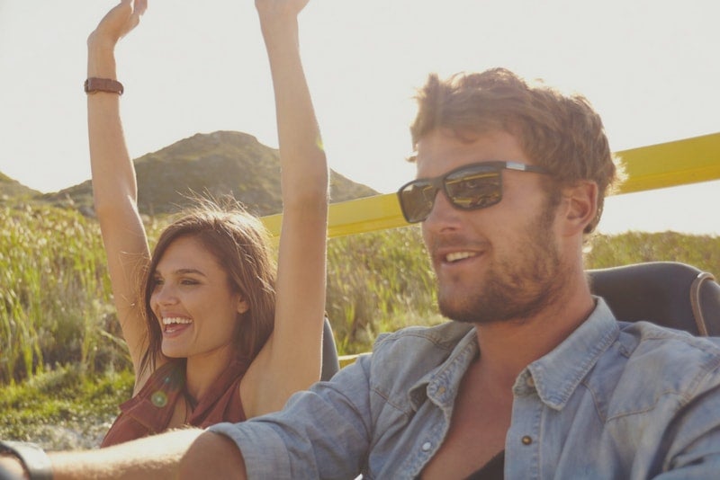 Man and woman riding in a convertible on vacation