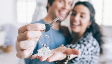 Couple holding key to first home after refinancing student loans