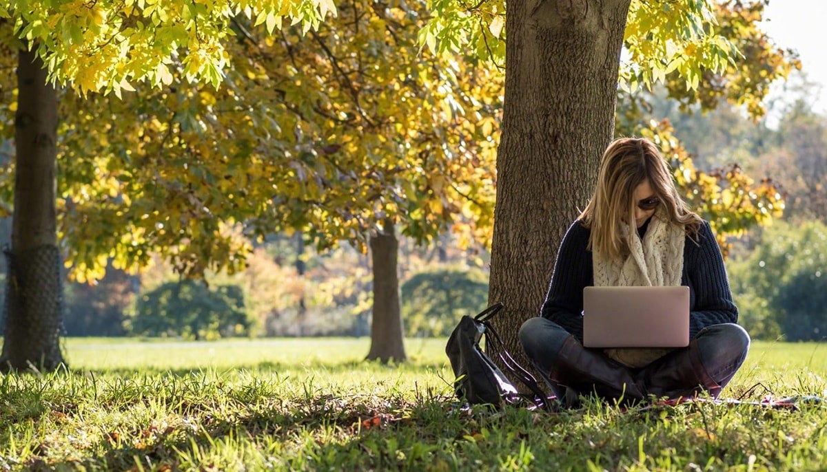 Women outside on computer looking at scholarships to attend college.