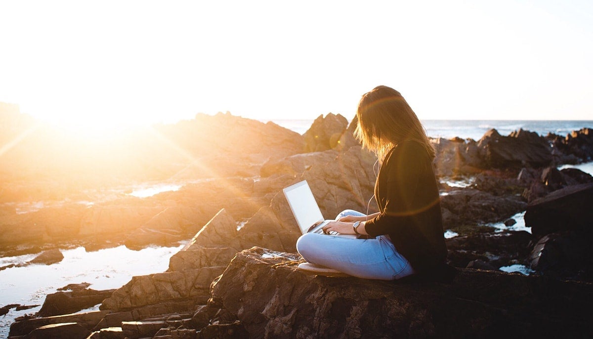 Girl looking to complete her FAFSA application before deadline while outside enjoying the sun and ocean.