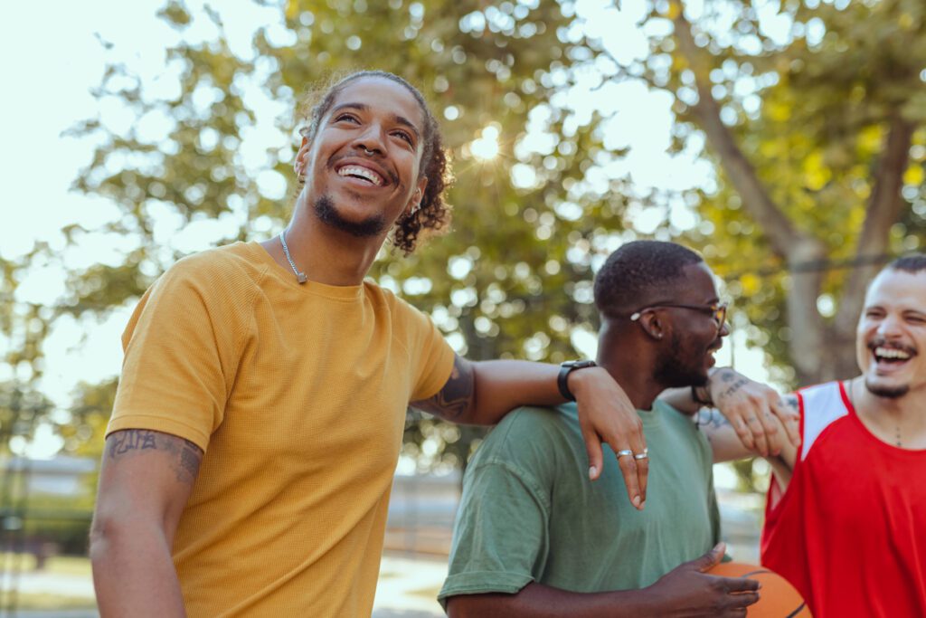 Happy male friends hanging out on the street basketball court