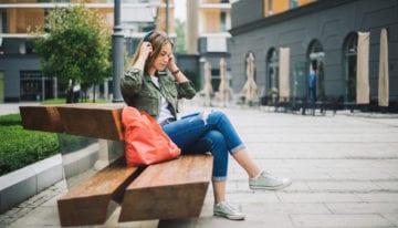 Woman enjoying podcast outdoors on a park bench