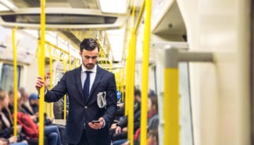 Man reading news about student loans on subway