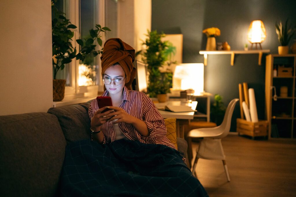Young woman using phone during the relaxing evening at home