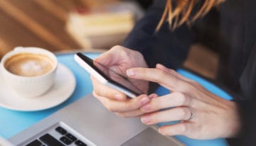 Person reading news about student loans in coffee shop