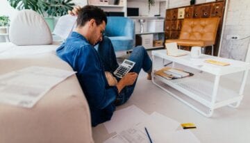Millennial man using a calculator to create budget