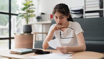 Young woman reviewing expenses with calculator