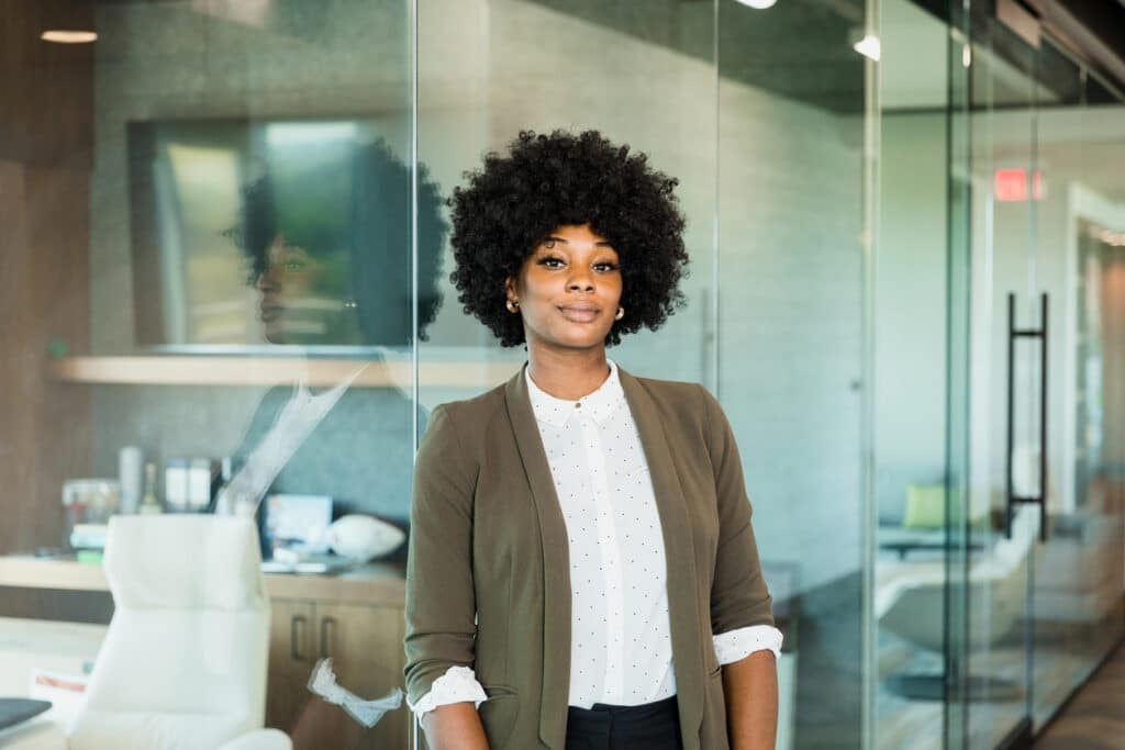 The confident, mid adult female lawyer leans against the glass wall of her office.