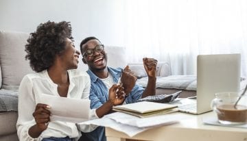 happy couple with paperwork and laptop