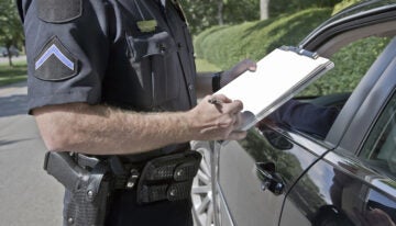 Police officer, with student loans, writes out a ticket.