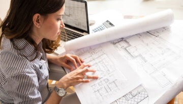 Female architect working on blueprint.