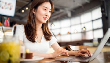 Asian female researching scholarships and grants to pay off student loans