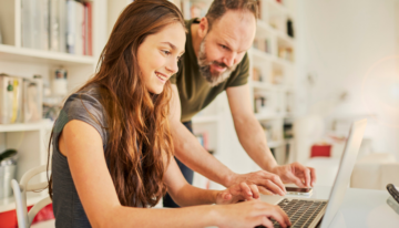 Father helping daughter fill out fafsa for school.