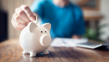 Person adding money to their piggy bank savings.