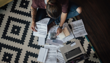 Person sitting with bills, impacted by student loan debt.