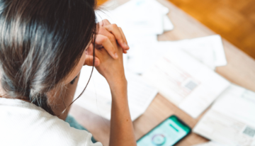 Woman sitting with bills and checking credit score.