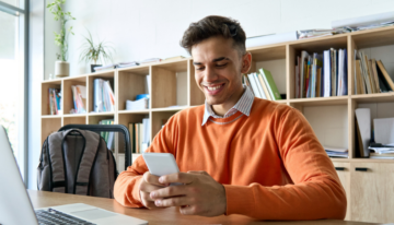 Young male student looking up scholarships on his phone.