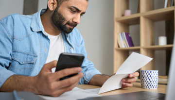 Man looking at paper and phone.