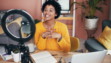 Young black female digital content creator taking a video on her phone.