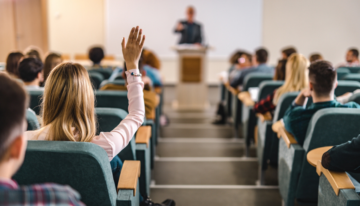 Student raising their hand in college lecture to ask a question.