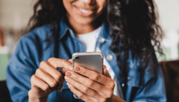 Black women using cell phone to look at social media.