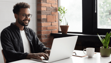 Black man sitting at his desk on computer.