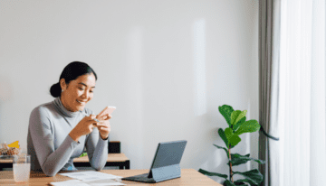 Young Asian woman looking at her credit score on her phone.