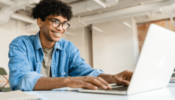 Young man looking at student loan forgiveness on his computer.