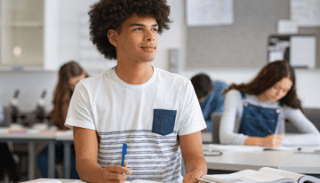 Young male high school student sitting in class.