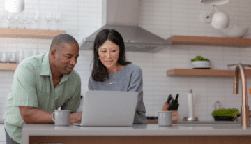 Mixed race couple looking at laptop in their kitchen