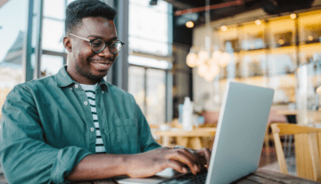 Young black male sitting in coffee shop on laptop.