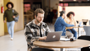 College student sitting in common area on computer.