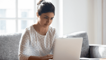 Young woman sitting at a table in her house on her laptop.