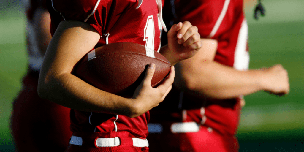 High school football players holding football.