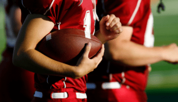 High school football players holding football.