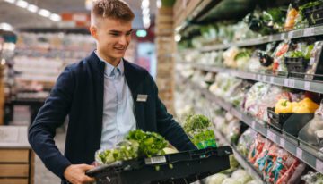 Young male high school student working part time job at grocery store
