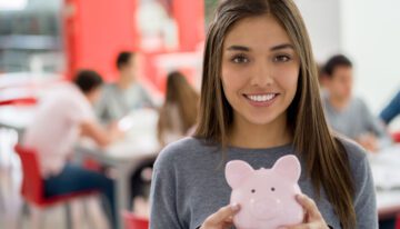 female student at the library holding a piggy bank