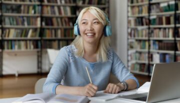 Young female asian student sitting in college library researching student loan payments.