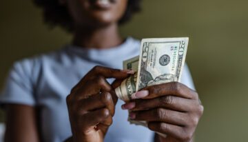 Close up of a woman counting money deciding on financing vs paying cash.