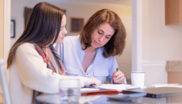 Mother looking over student loan paperwork to cosign loan for daughter.