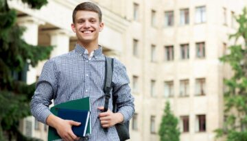 Young male standing on college campus after learning about scholarships for law school.