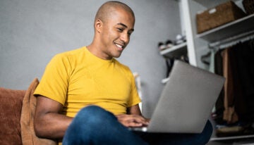 Young man using their laptop to research the best student loan rates.