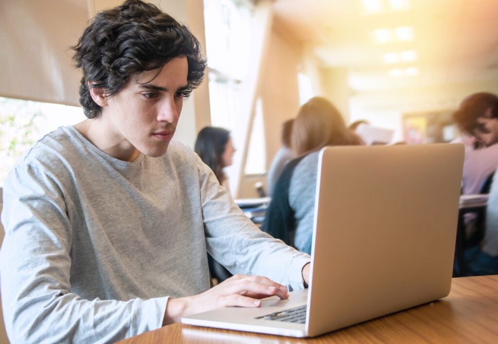 male college student looking up changes to the FAFSA on laptop
