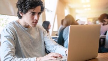 male college student looking up changes to the FAFSA on laptop