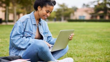 College female looking up tuition insurance on laptop outside of college
