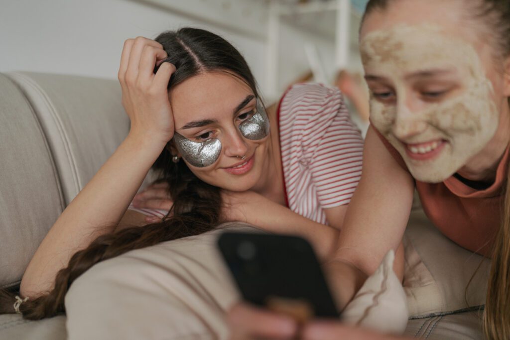 Photo of two young women, university students, performing skincare routine while having Girl's night in, in their college dorm room