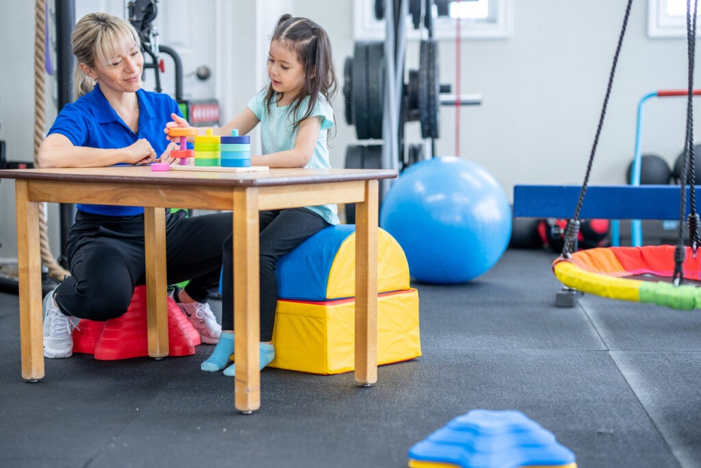 Occupational therapy student who used occupational therapy scholarship for school helping a child with therapy.