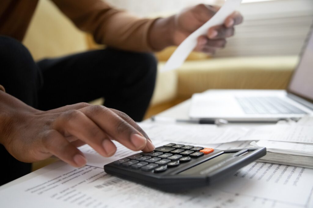 Person prioritizing debts by using a calculator.