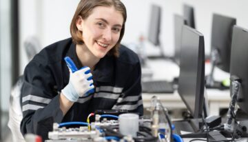 Female student working on computer hardware in class after using scholarship for computer engineering.