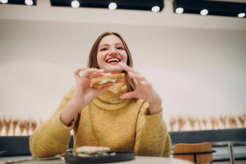 Young woman eating sandwich at indoor cafe